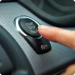 Finger pressing a car’s start-stop button