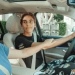 Parent guiding a teenage driver in a car, holding their arm to offer advice or encouragement