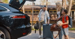 A family loading luggage into the back of a car, preparing for a trip