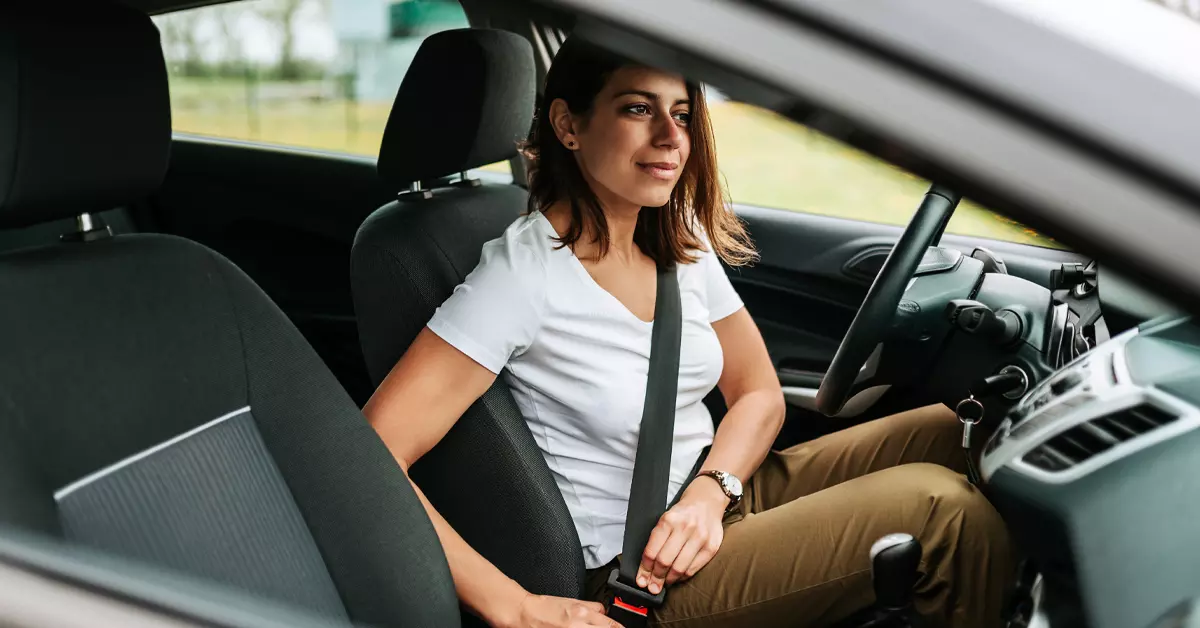 A woman putting on a seat belt.