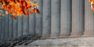 Marble courthouse steps with large columns framed by autumn leaves