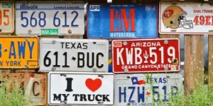 Collection of license plates, including ones from Texas, Arizona, and Illinois, displayed on a wooden fence
