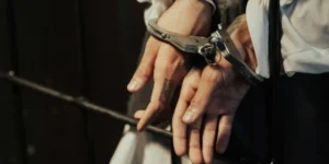 Hands in handcuffs behind bars, representing arrest and legal consequences after a DUI