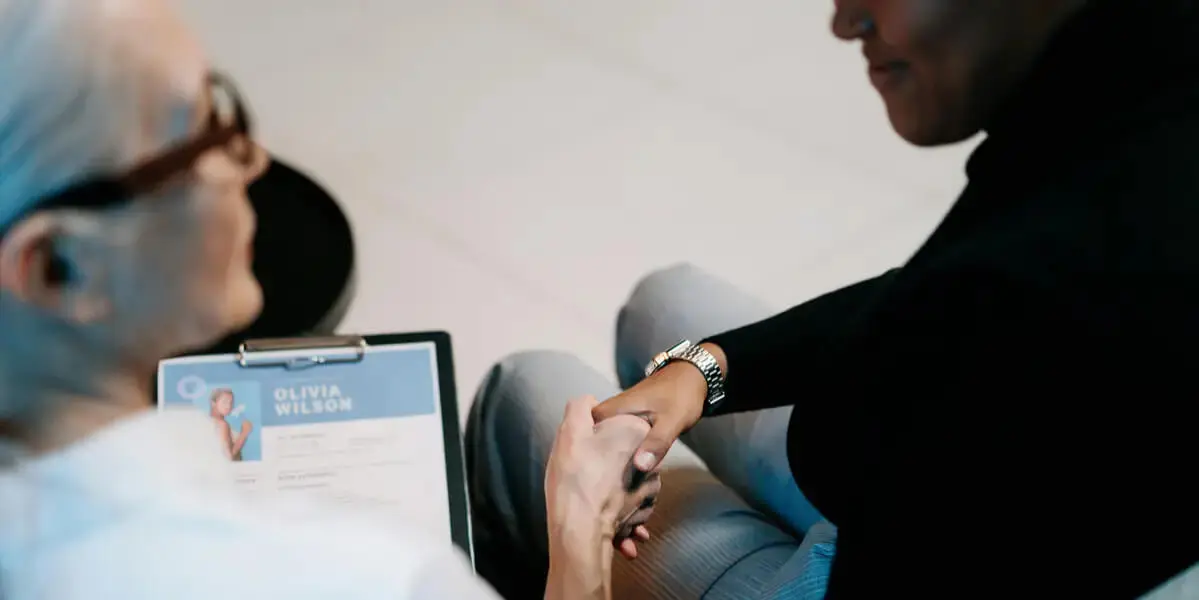 Employer reviewing a resume and shaking hands with a job applicant during an interview