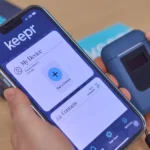 Person holding a smartphone displaying the Keepr app interface next to a compact Keepr personal breathalyzer device