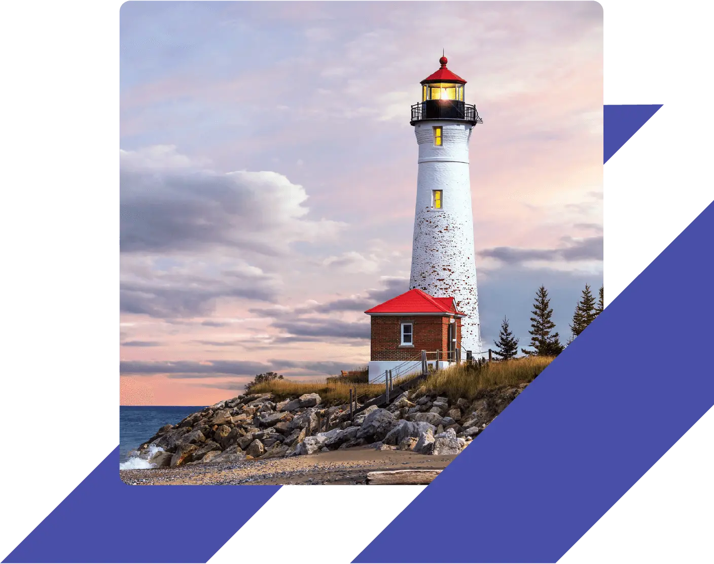White lighthouse on a rocky shoreline under a colorful sunset
