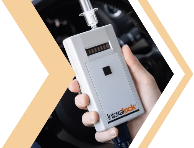 Person holding an Intoxalock ignition interlock device inside a vehicle