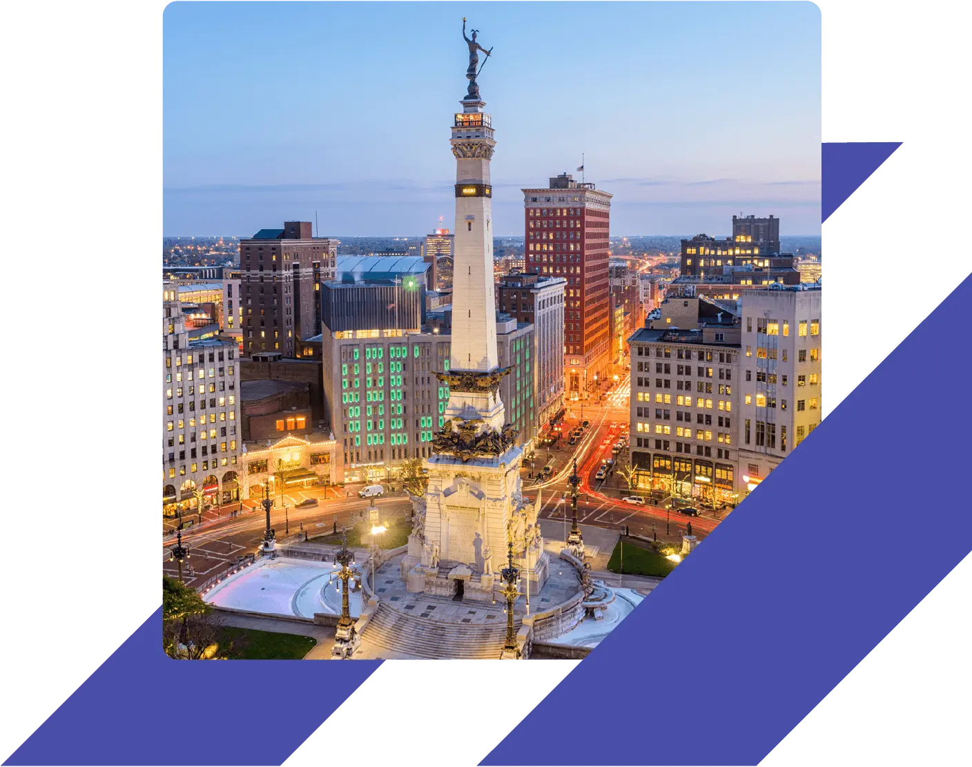 Soldiers and Sailors Monument in downtown Indianapolis, Indiana, illuminated at dusk with surrounding city buildings.