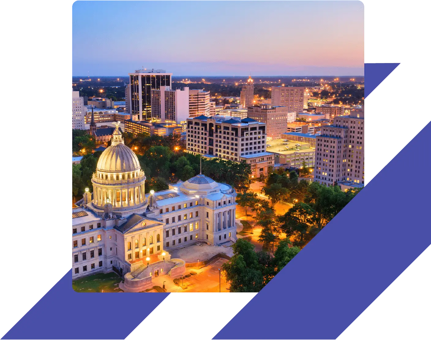 The Mississippi State Capitol lit up at dusk, with downtown Jackson’s city skyline in the background.