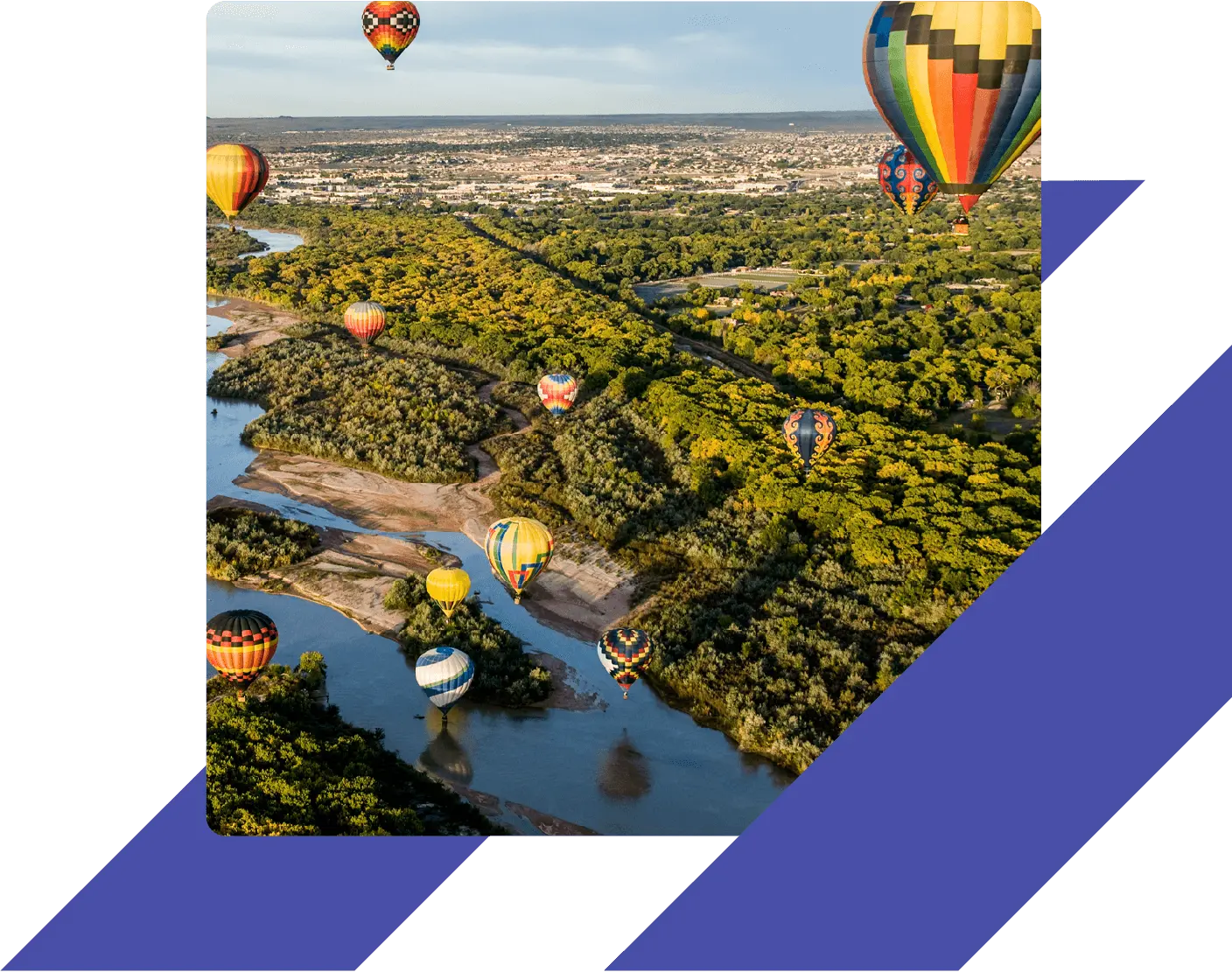 Colorful hot air balloons floating over the Rio Grande and forested landscape near Albuquerque, New Mexico, during a clear day.