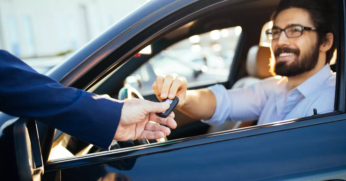 Person handing a key fob to another person trough a car window.