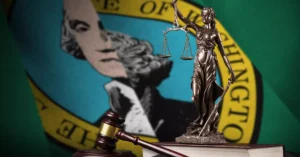 Bronze statue of Lady Justice holding scales and a sword placed in the front of a flag, symbolizing fairness and the judicial system.