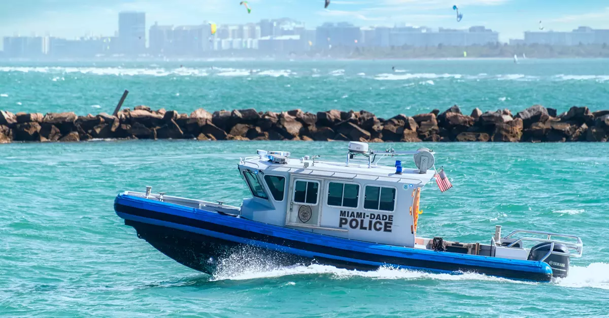 A police boat seen from the side, moving quickly trough water.