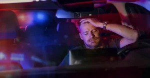 A man sitting in his car getting pulled over by a police vehicle.