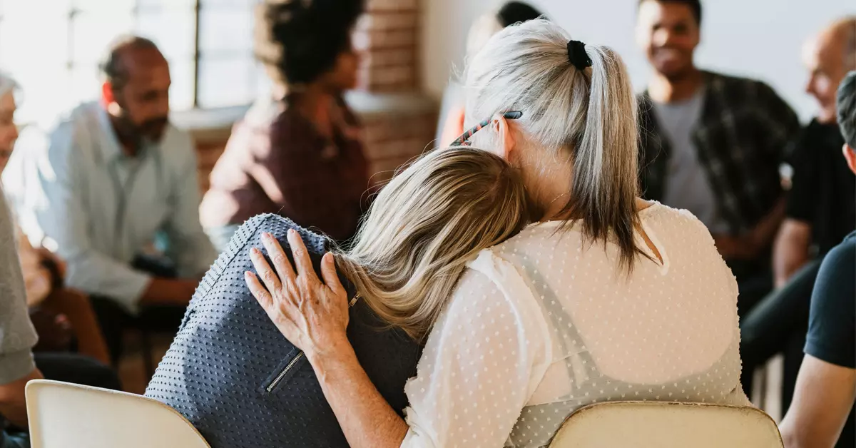 Two women consoling each other at a meeting.
