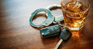 A picture of a pair of handcuffs next to set of car keys, and a whiskey glass.